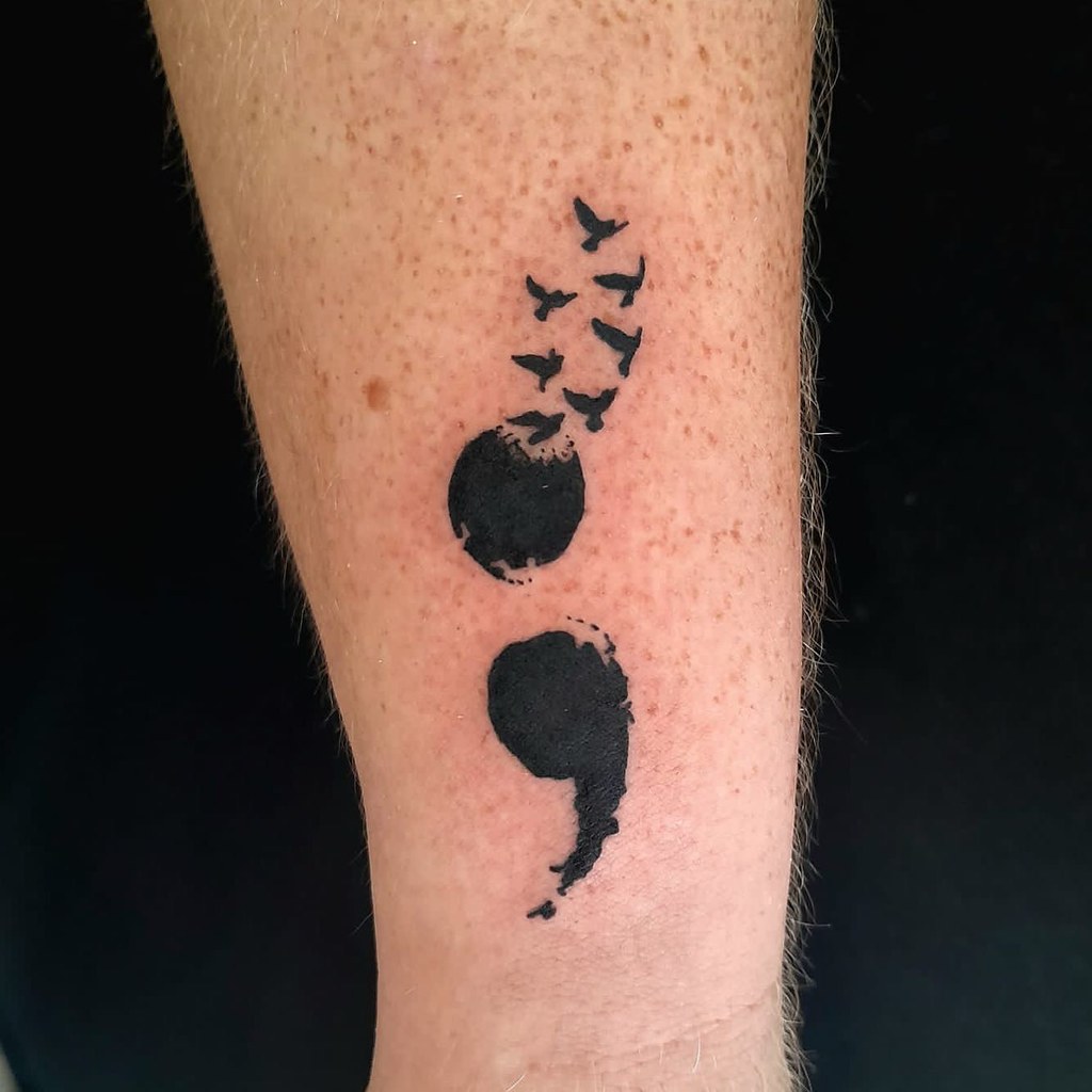 Semicolon tattoo with birds on a lower leg
