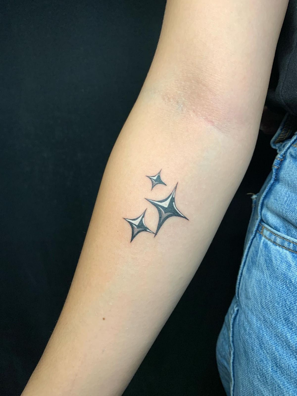 Small sparkle star tattoos on a forearm