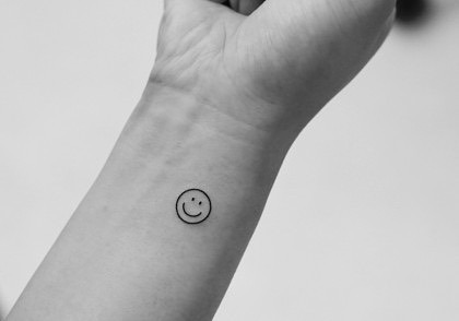 Charming minimalist smiley face tattoo on wrist Tattoo Design