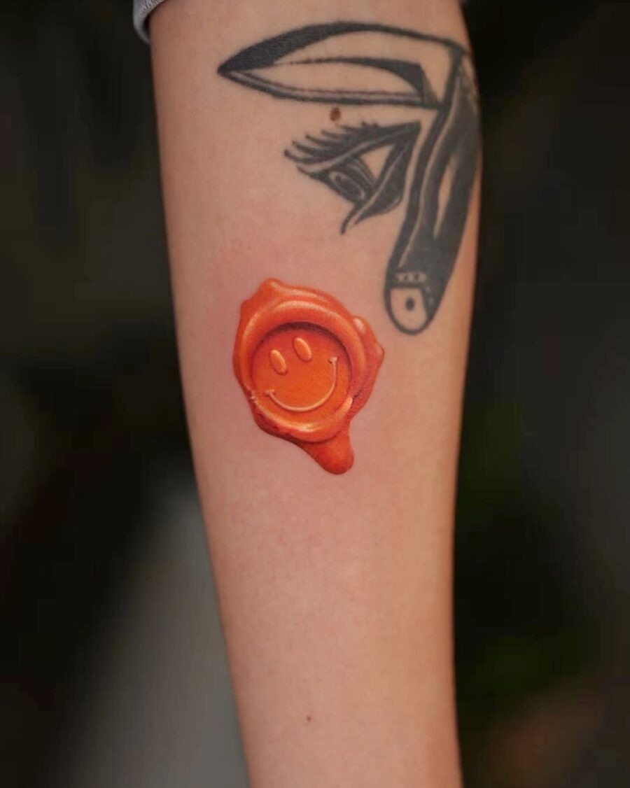 Vibrant Orange Smiley Face Tattoo on Arm Tattoo Design