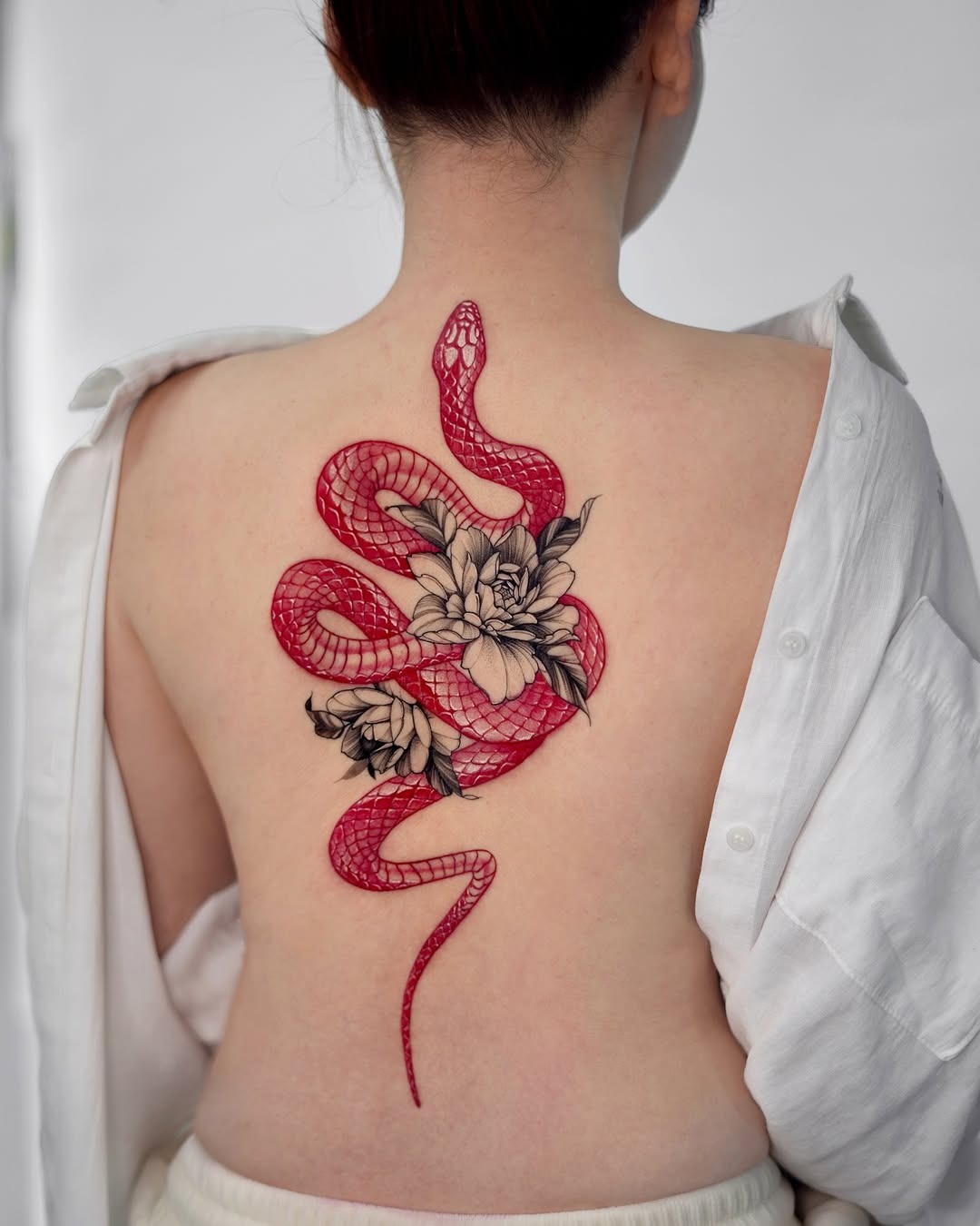 Elegant red snake tattoo with floral accents Tattoo Design