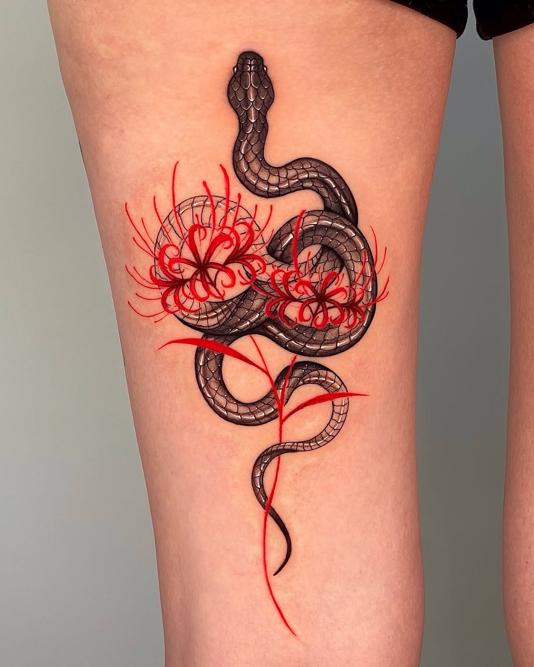 Elegant snake tattoo entwined with vibrant blooms Tattoo Design
