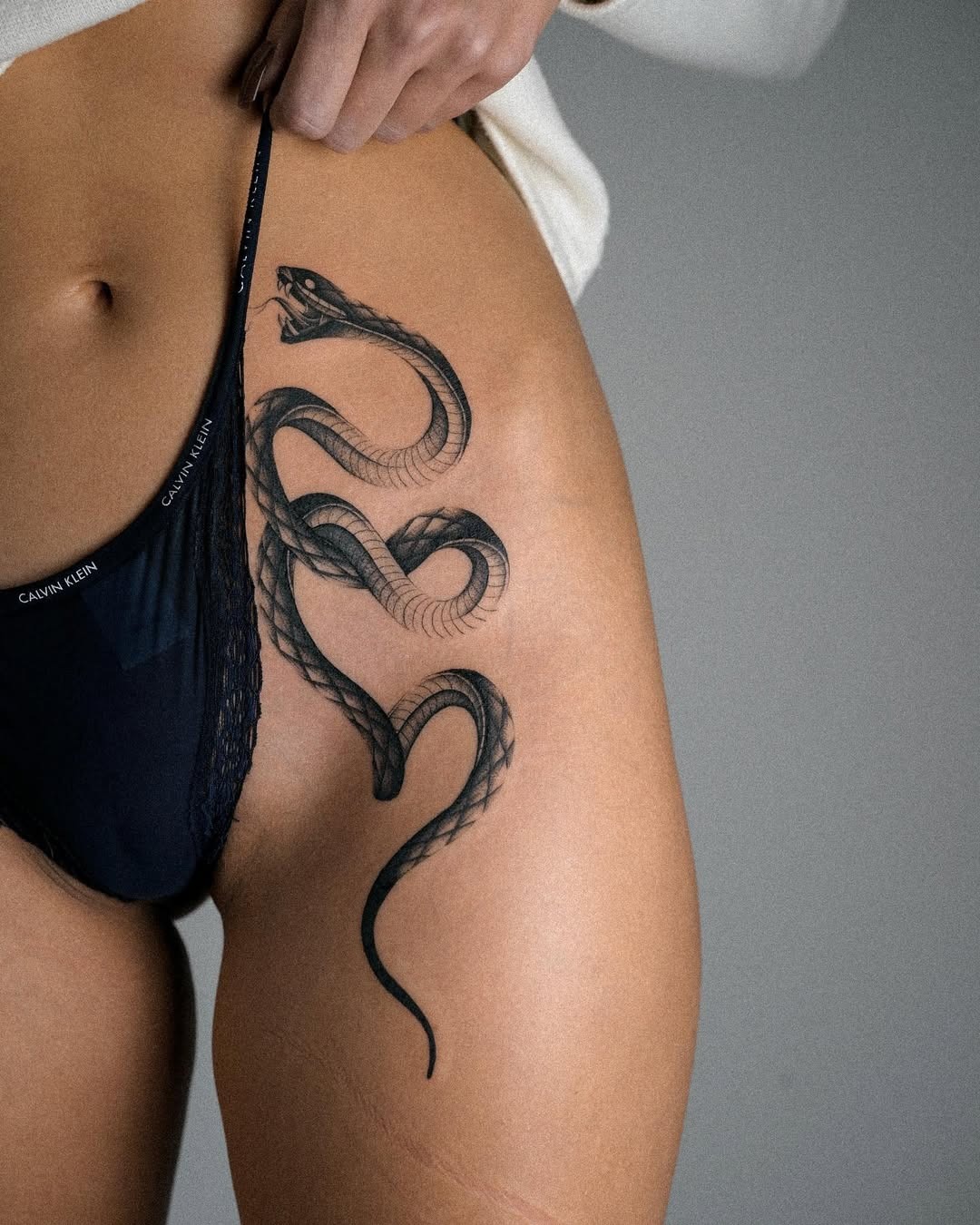 Elegant snake tattoo on thigh for bold expression Tattoo Design