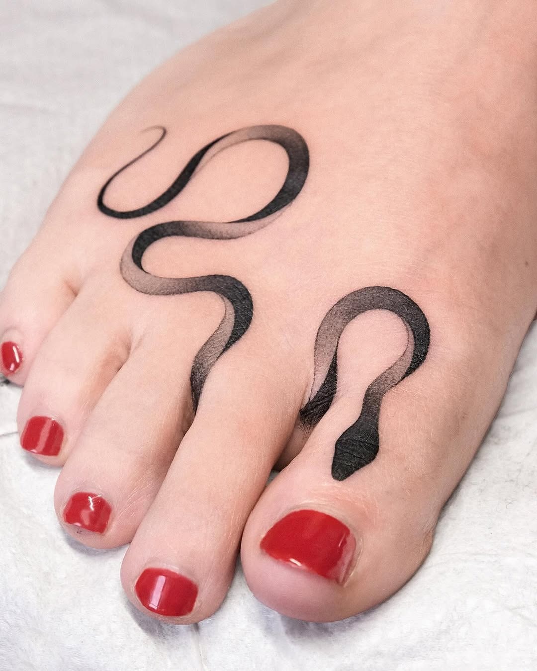 Elegant snake tattoo wrapping around the foot Tattoo Design