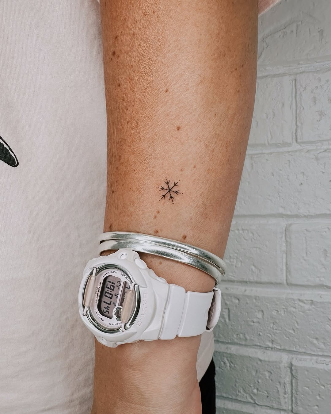 Delicate snowflake tattoo on wrist with accessories Tattoo Design