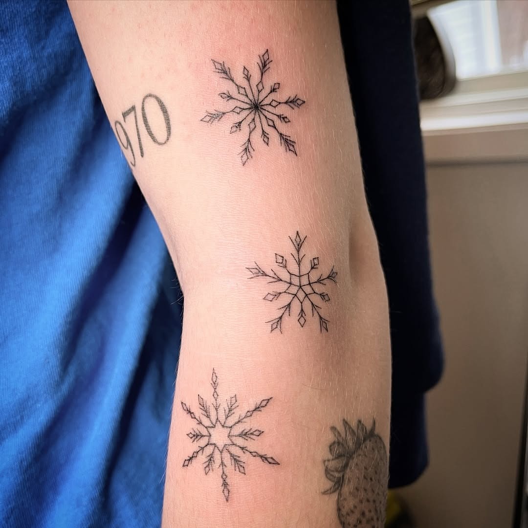 Elegant black ink snowflake tattoo arrangement Tattoo Design