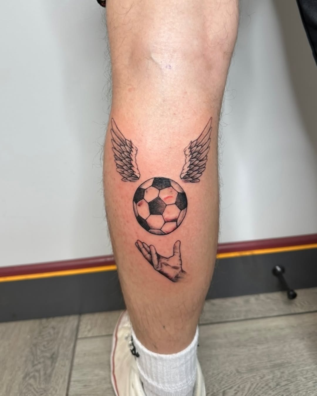 Winged Soccer Ball Tattoo with Hand Gesture Tattoo Design