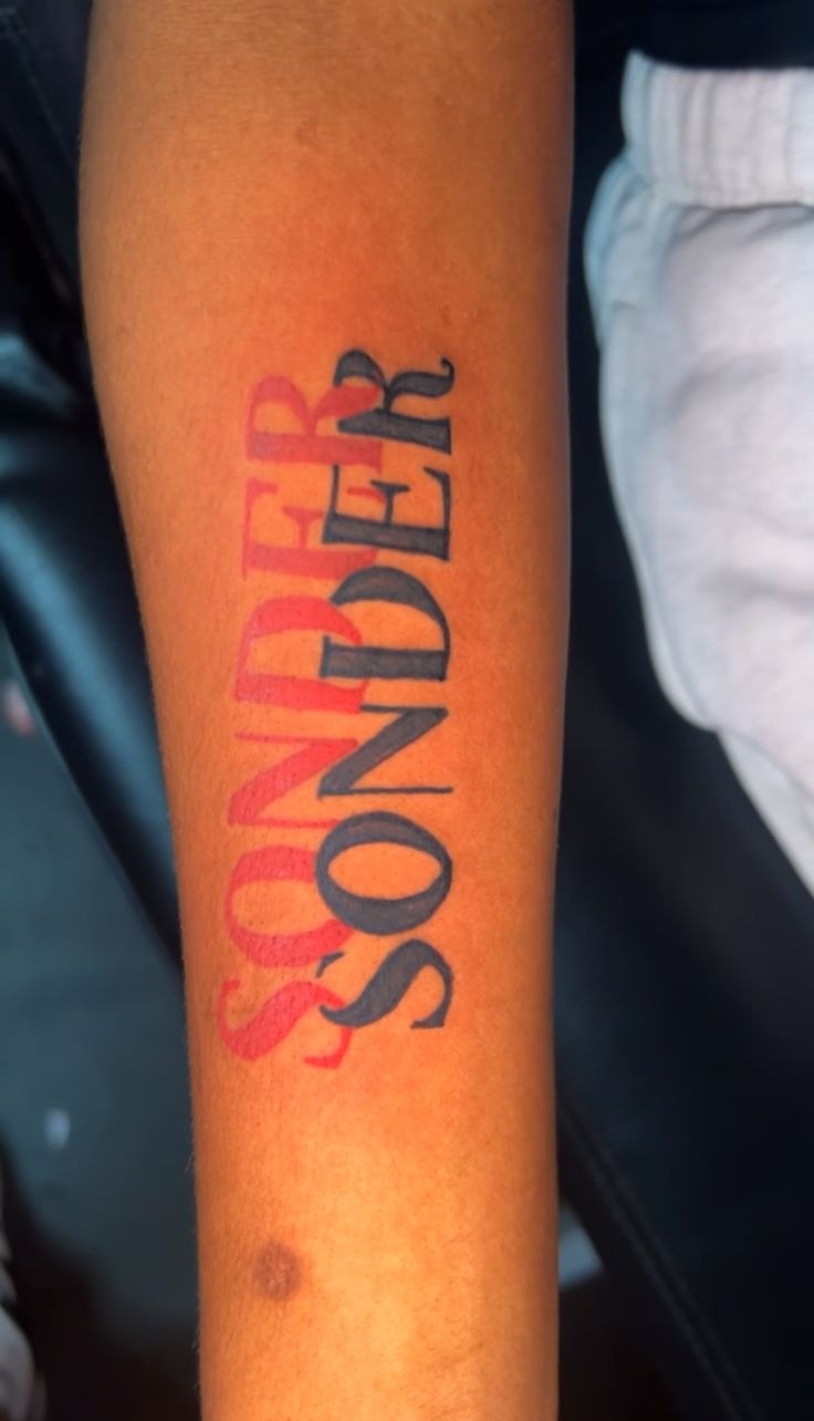 High-Contrast Red and Black Sonder Forearm Tattoo Design