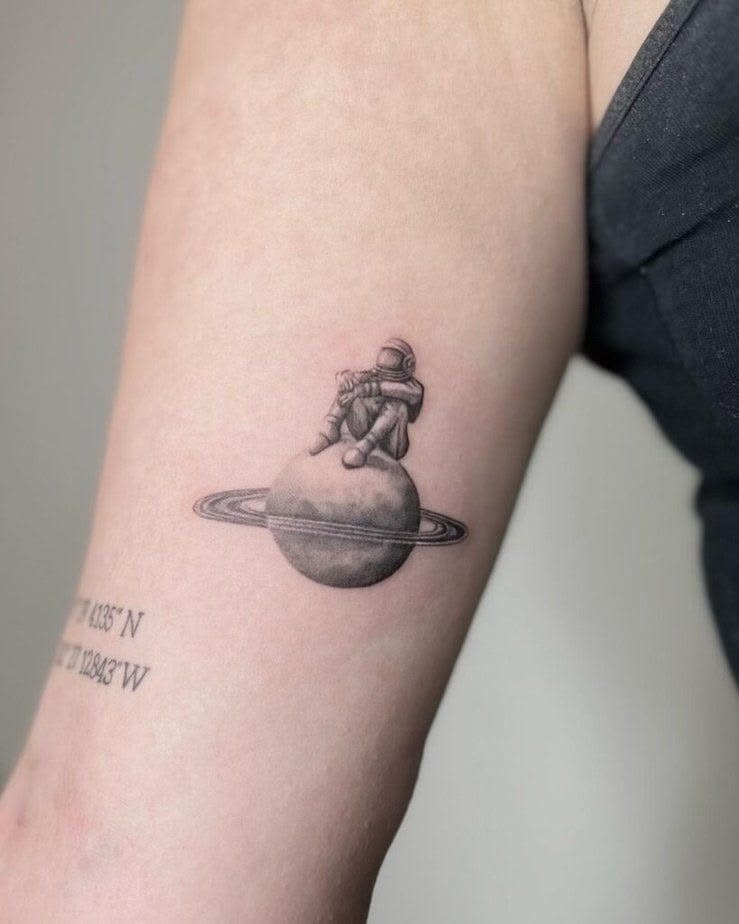 Quiet Astronaut Sitting on Saturn Tattoo Design