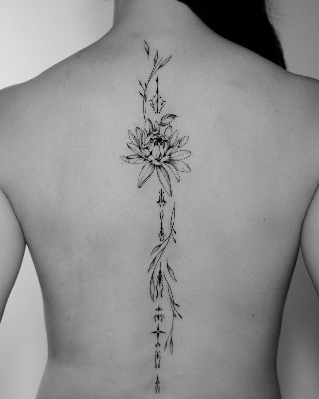 Elegant floral spine tattoo design in black ink Tattoo Design