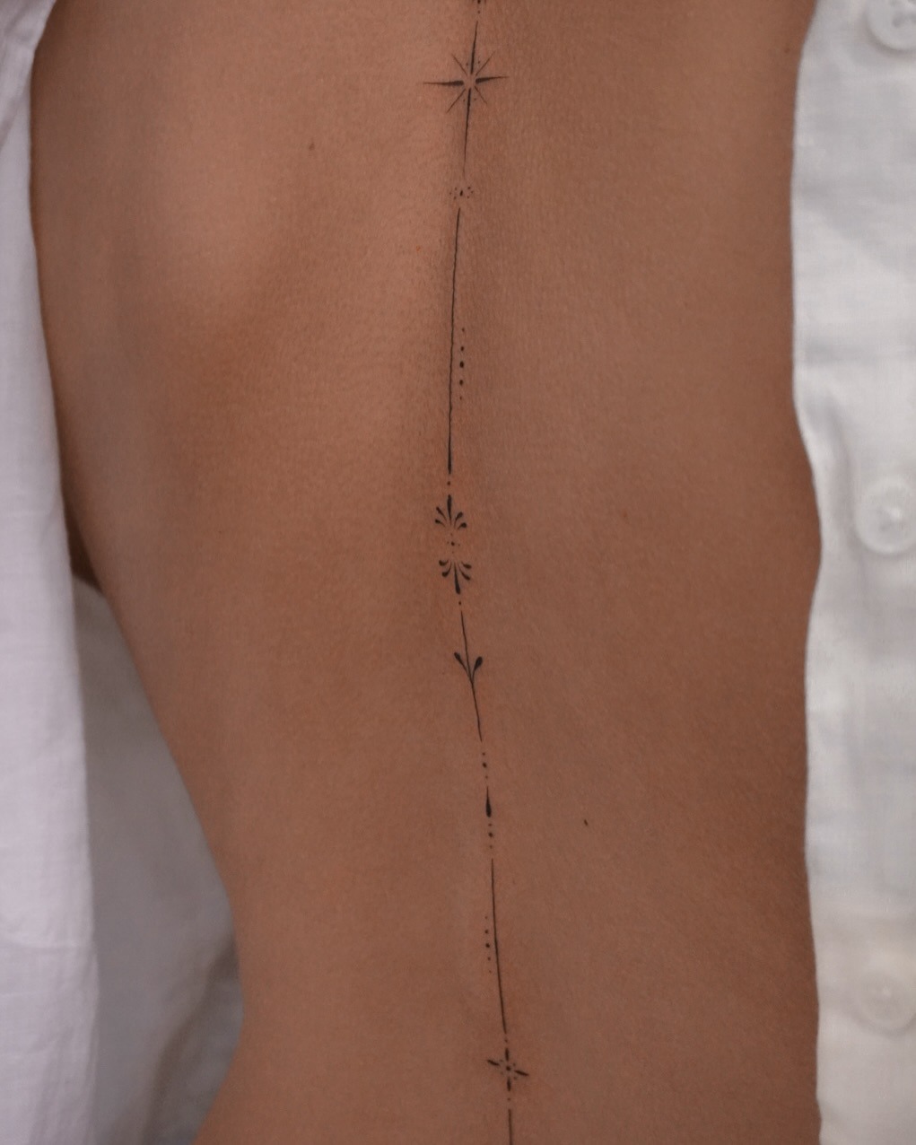 Elegant spine tattoo featuring floral accents Tattoo Design