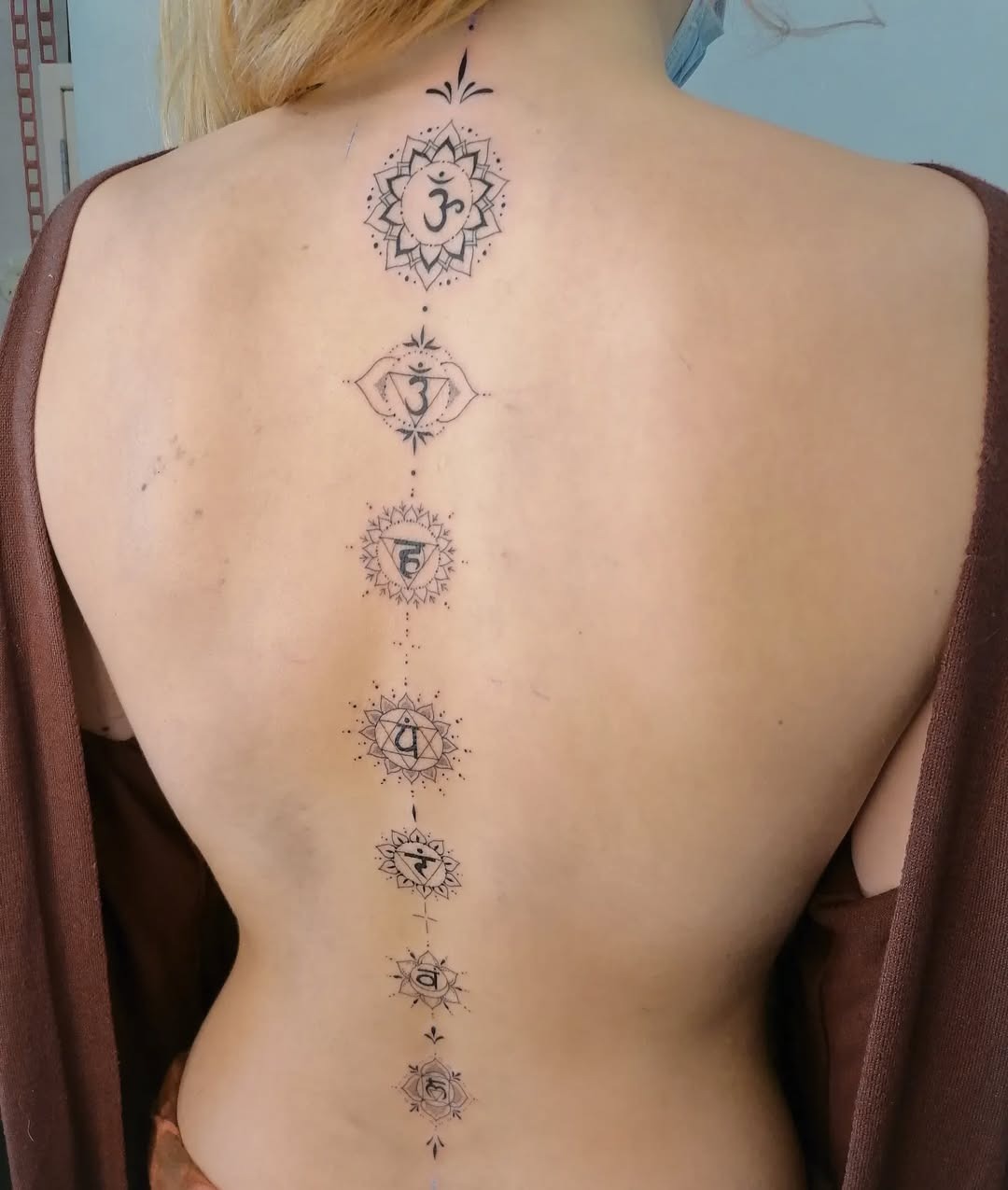 Elegant spine tattoo showcasing chakra symbols Tattoo Design