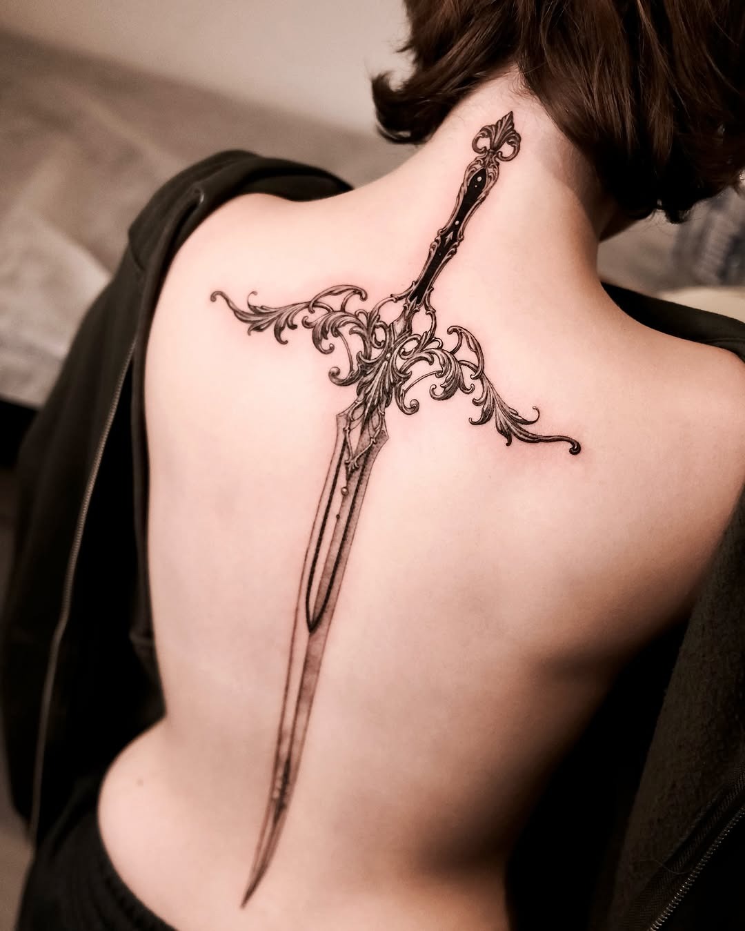 Intricate sword tattoo adorning the spine Tattoo Design