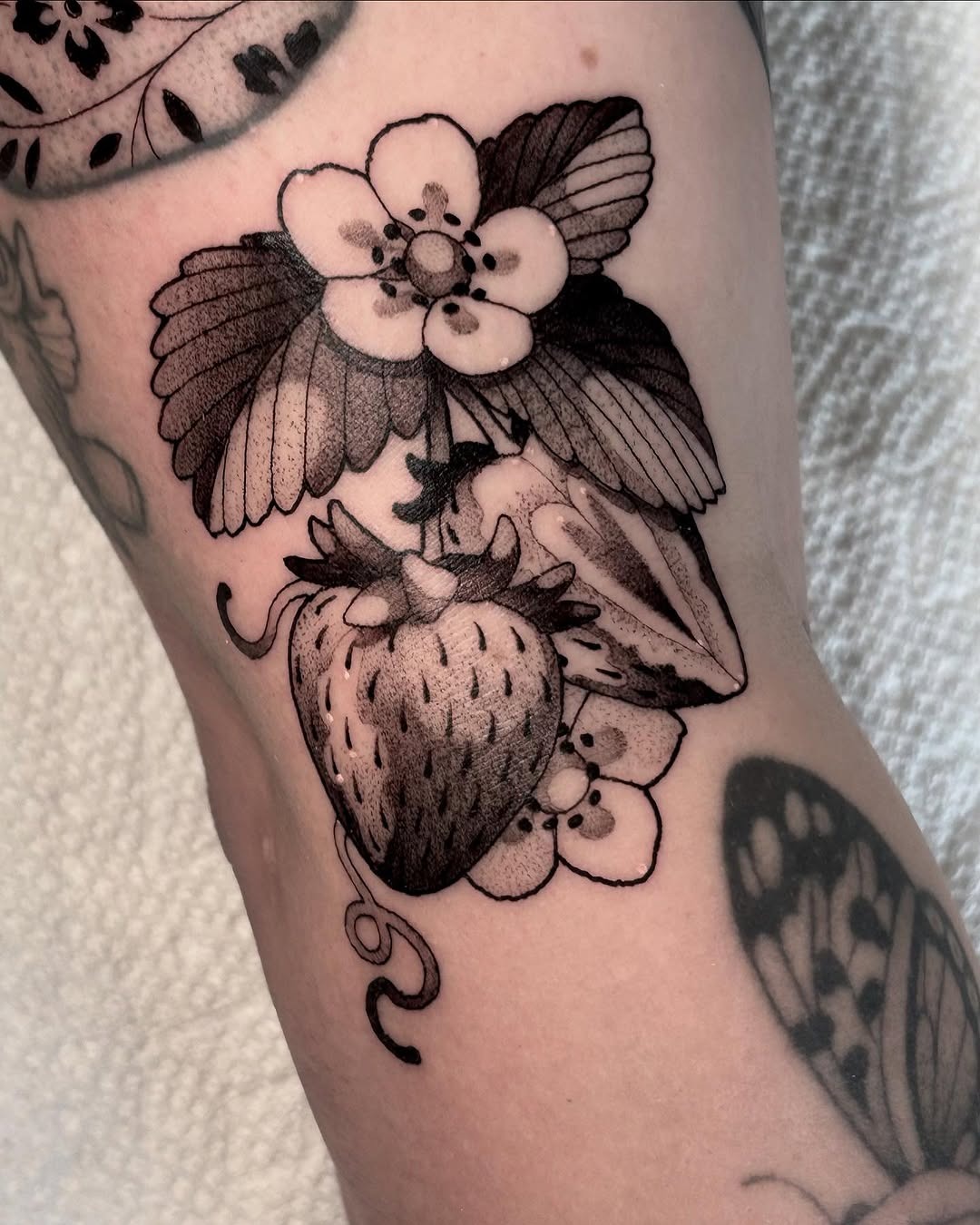 Elegant strawberry tattoo with floral details Tattoo Design