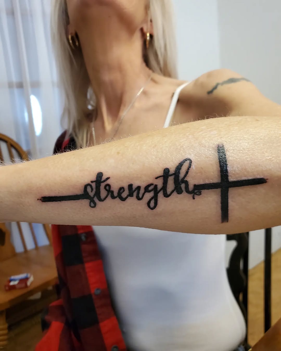 Meaningful strength tattoo featuring bold strength tattoo with cross design in bold black ink
