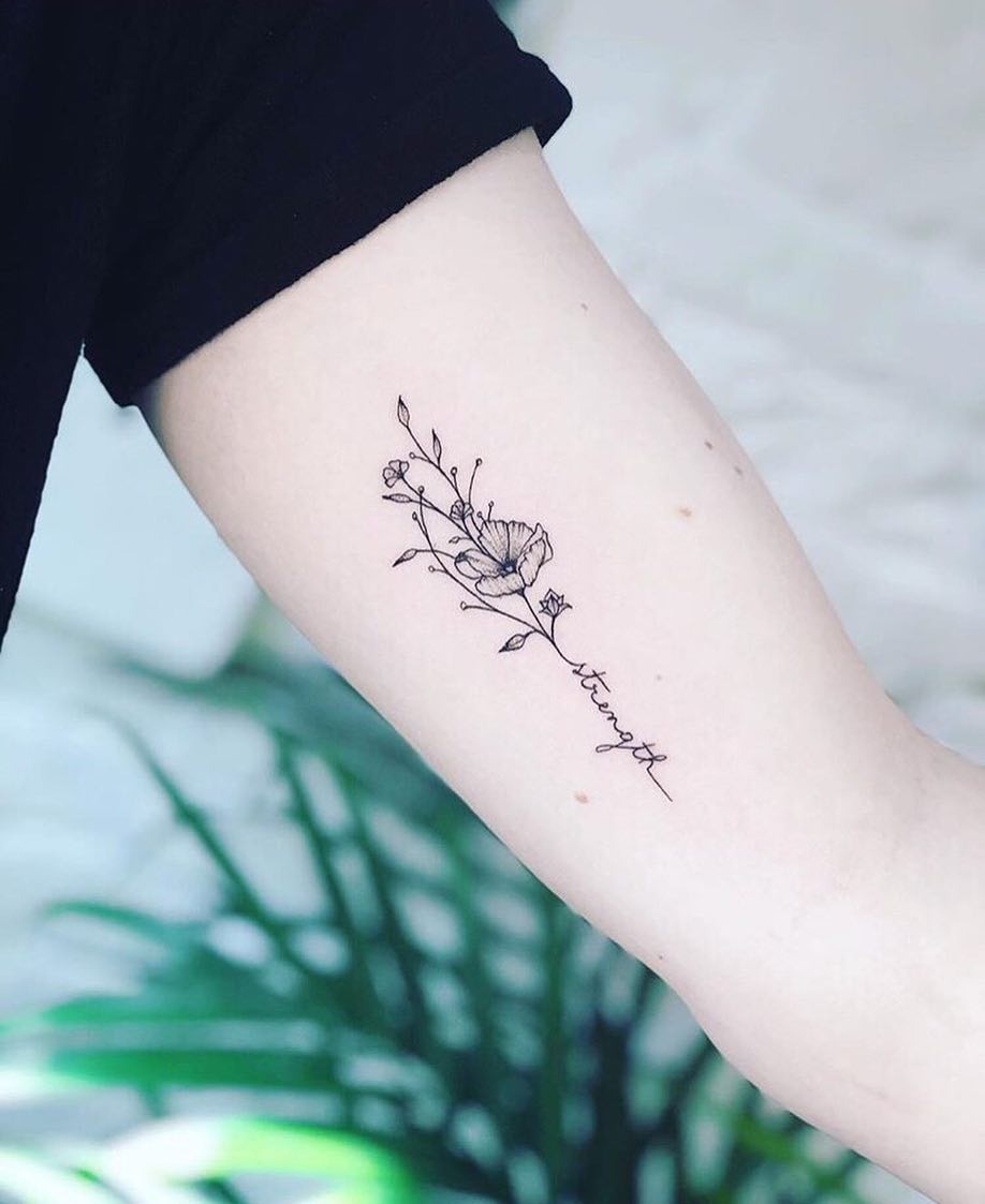 Meaningful strength tattoo featuring elegant floral strength tattoo on the arm in bold black ink
