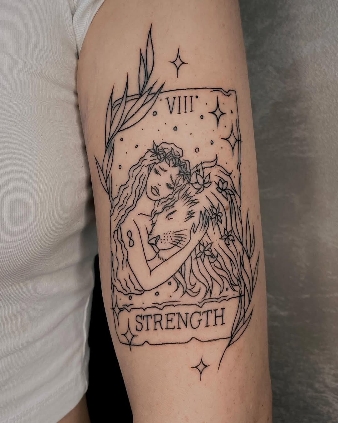 Meaningful strength tattoo featuring elegant strength tattoo merging nature and power in bold black ink