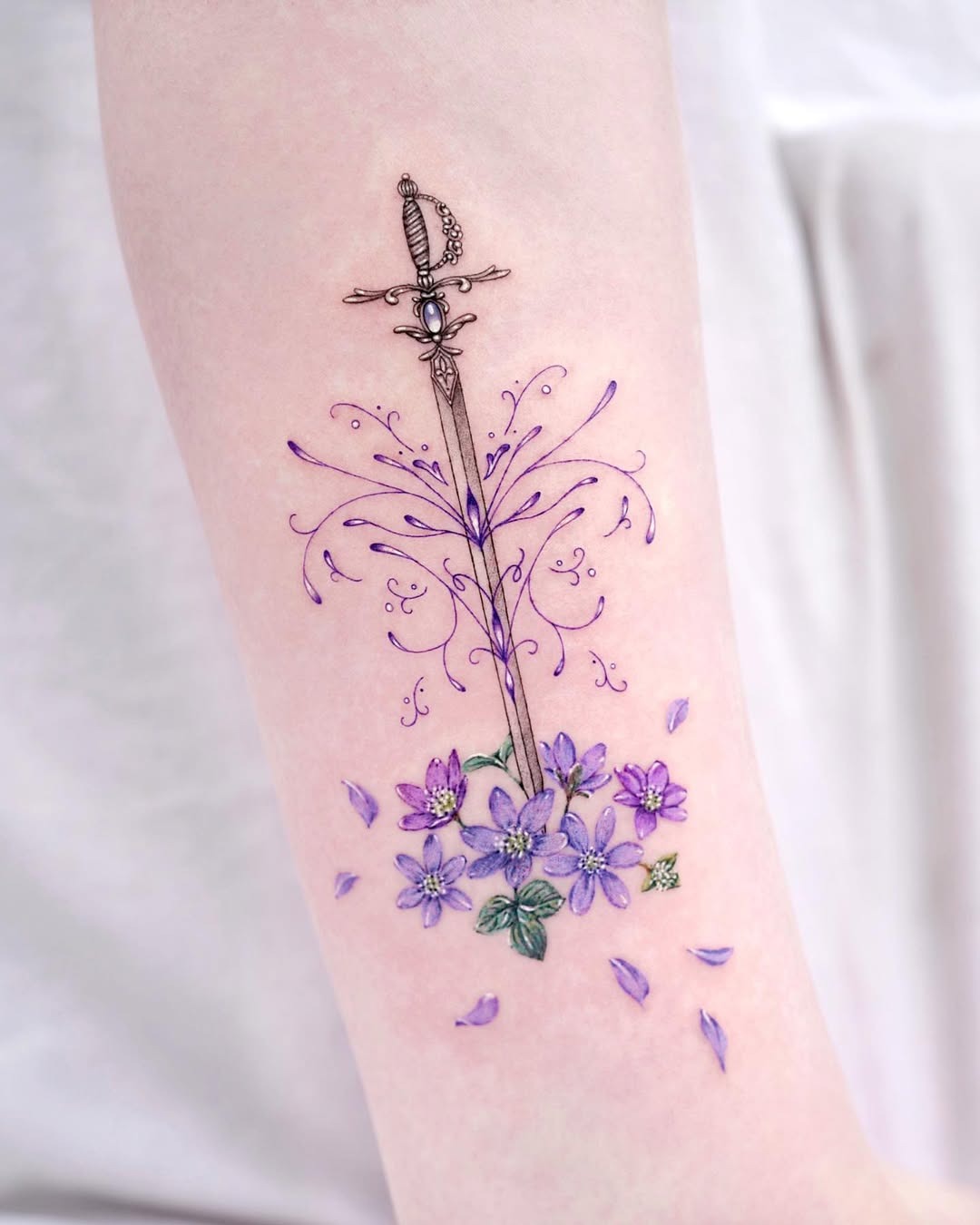 Meaningful strength tattoo featuring floral sword tattoo representing inner strength in bold black ink