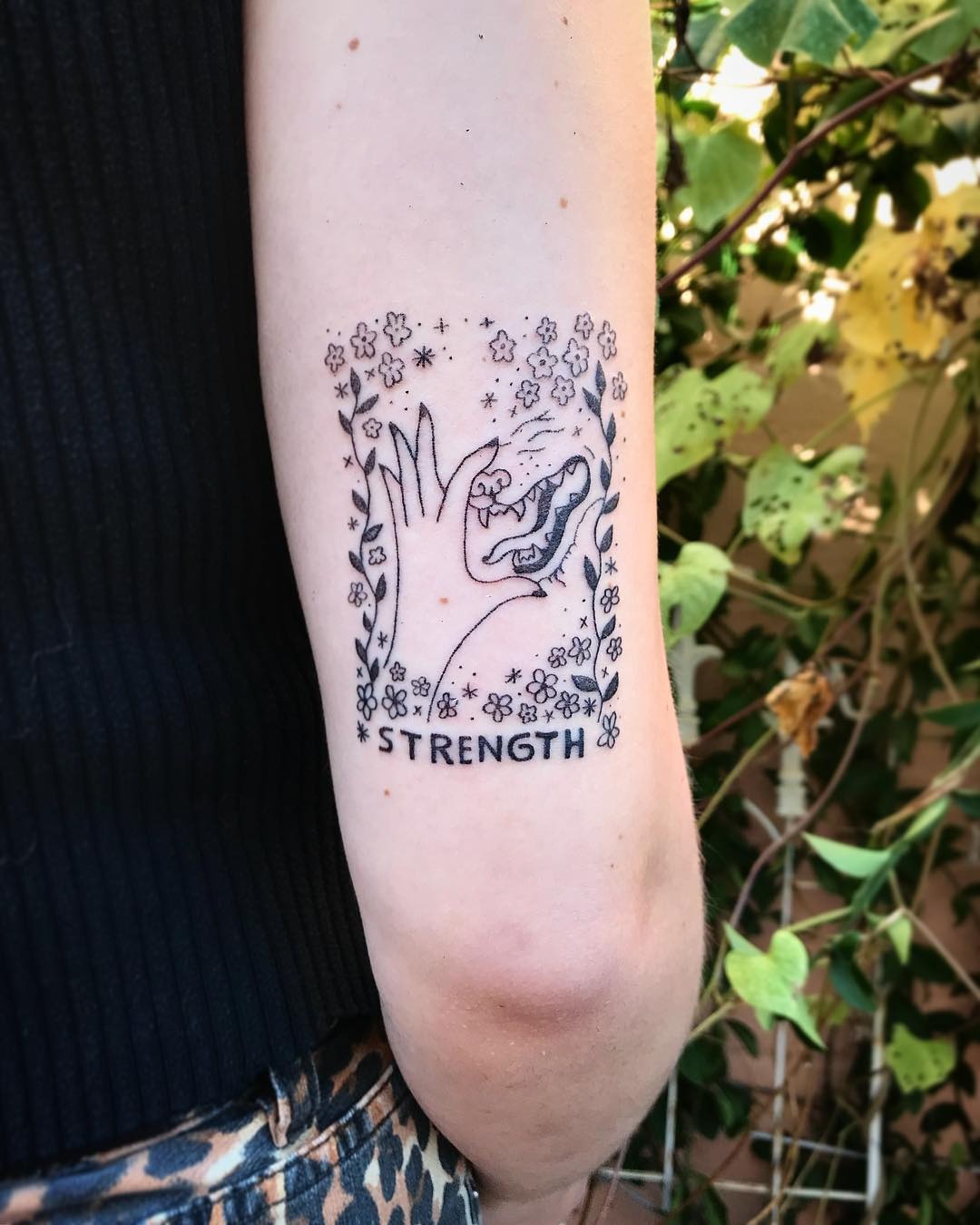 Meaningful strength tattoo featuring nature inspired strength tattoo design in bold black ink