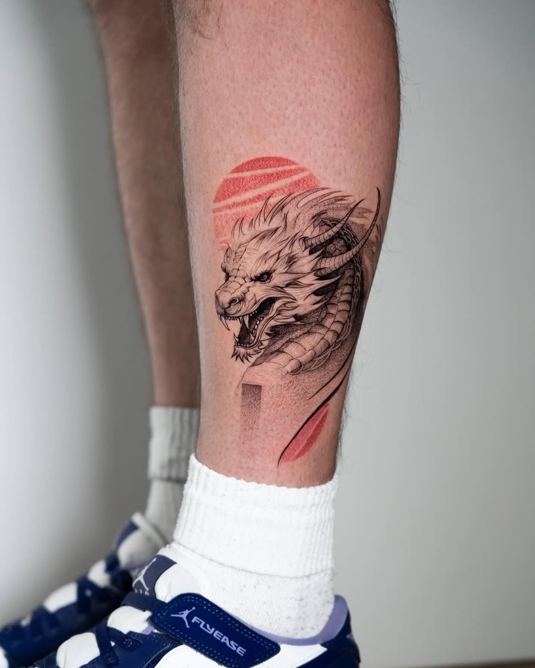 Meaningful strength tattoo featuring powerful dragon tattoo on calf exudes strength in bold black ink