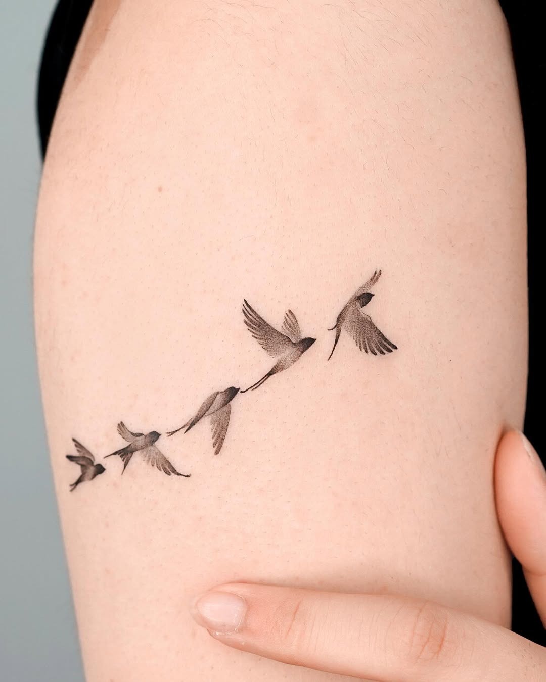 Meaningful strength tattoo featuring symbolic birds portraying freedom and strength in bold black ink