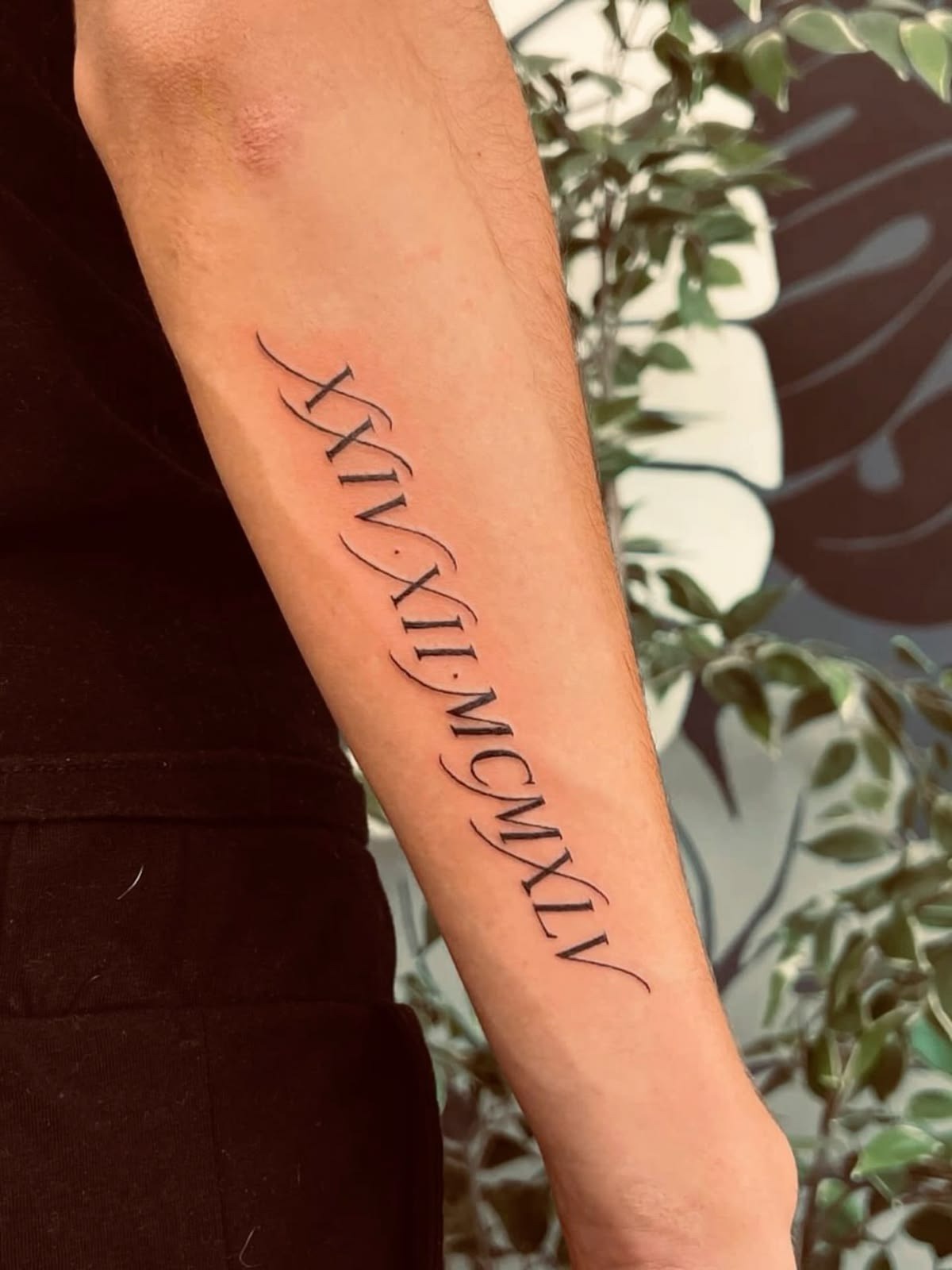 Elegant Cursive-Inspired Roman Numeral Forearm Tattoo Tattoo Design