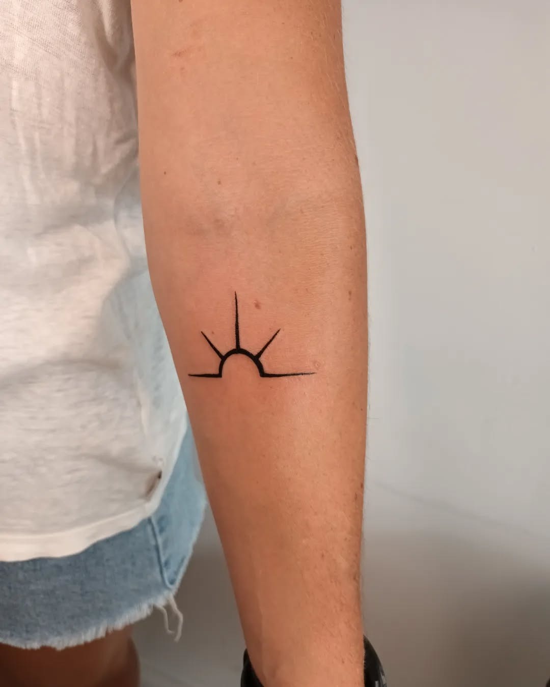 Minimalist black sunrise tattoo on arm Tattoo Design
