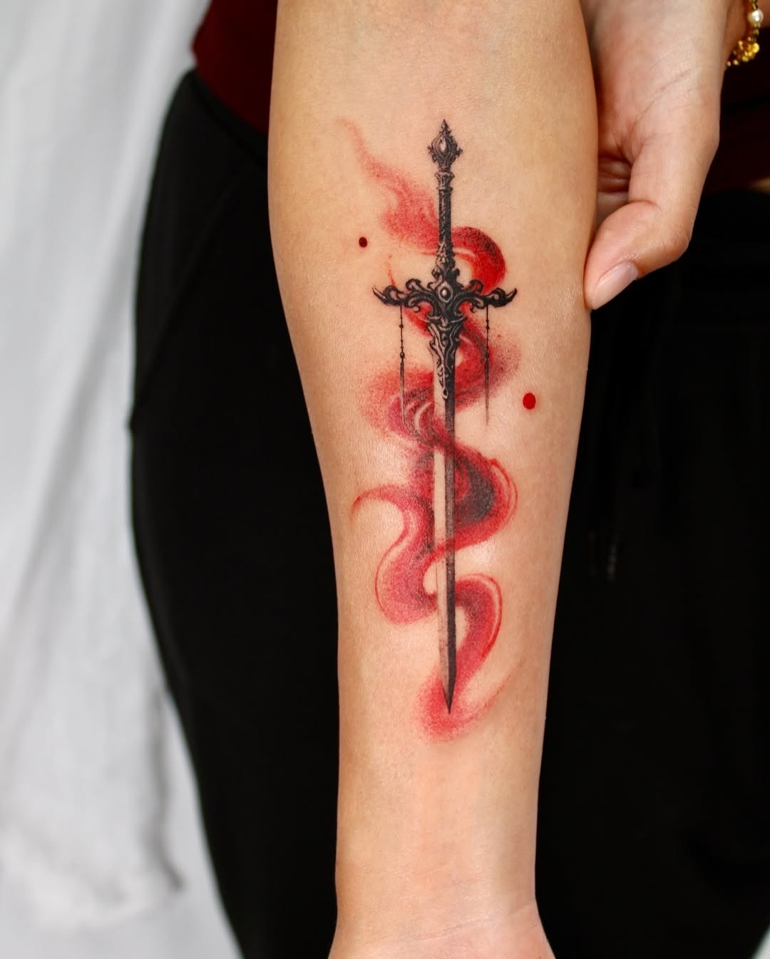 Intricate sword tattoo with vibrant red swirls Tattoo Design