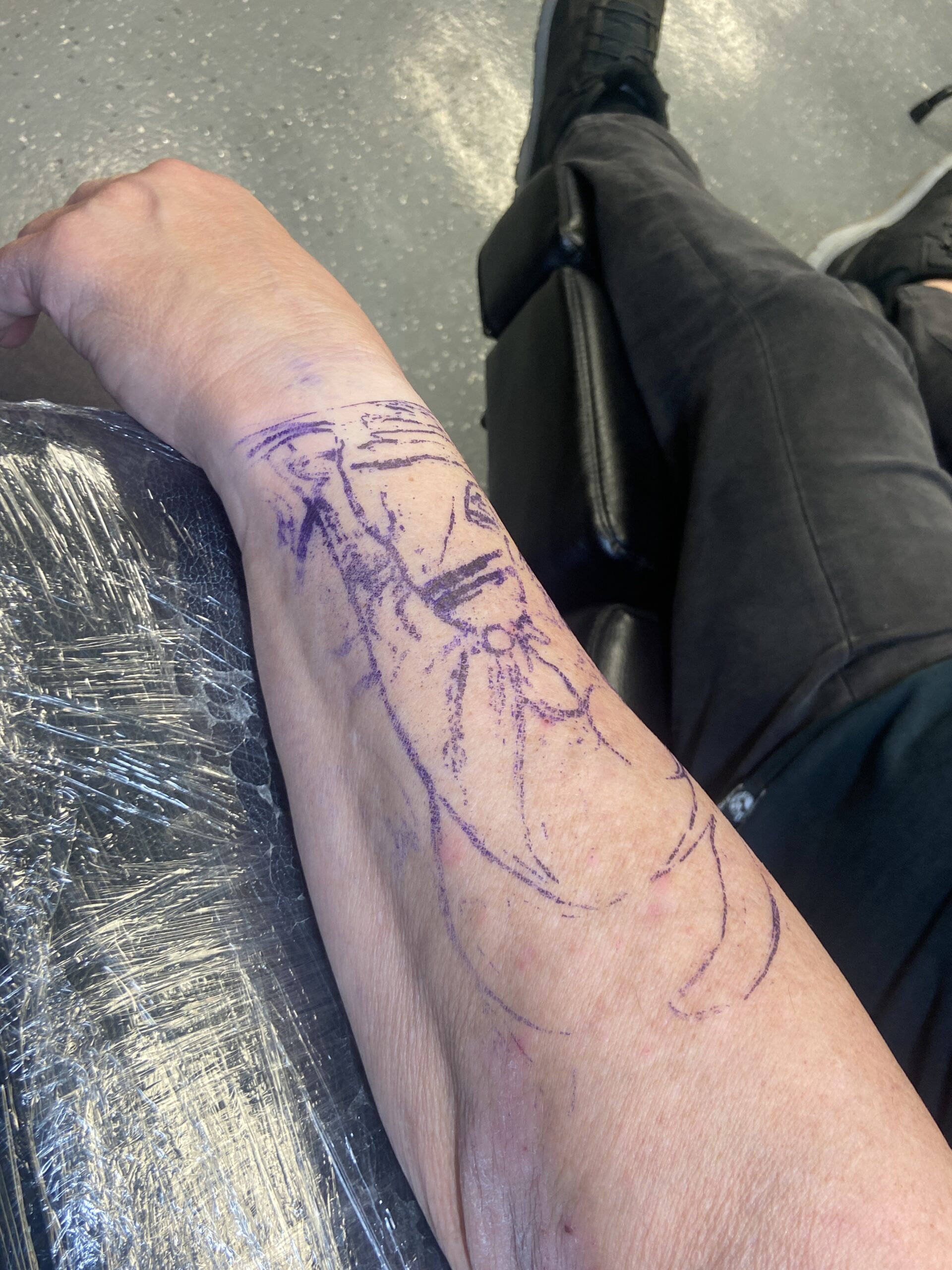 A purple tattoo stencil transferred onto a client's skin for placement review before tattooing.