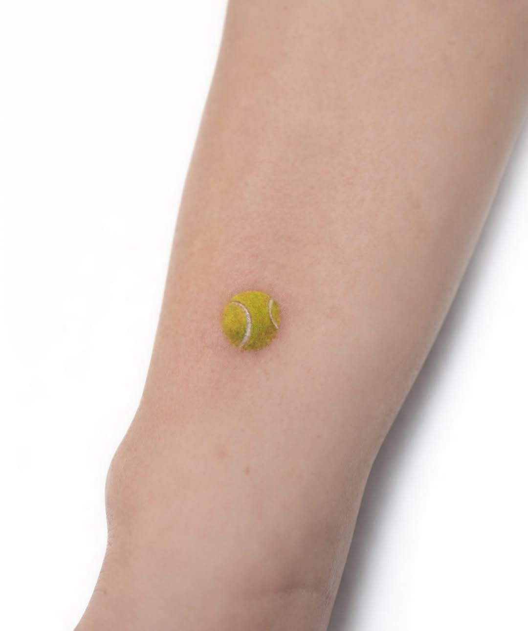 Minimalist tennis ball tattoo on the arm Tattoo Design