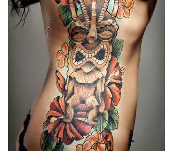 Wooden Tiki Statue With Cascading Flowers Tattoo Design