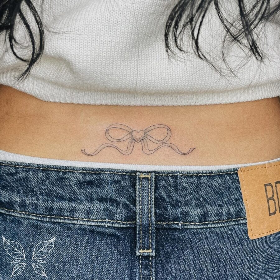 Delicate bow tattoo with a heart accent Tattoo Design