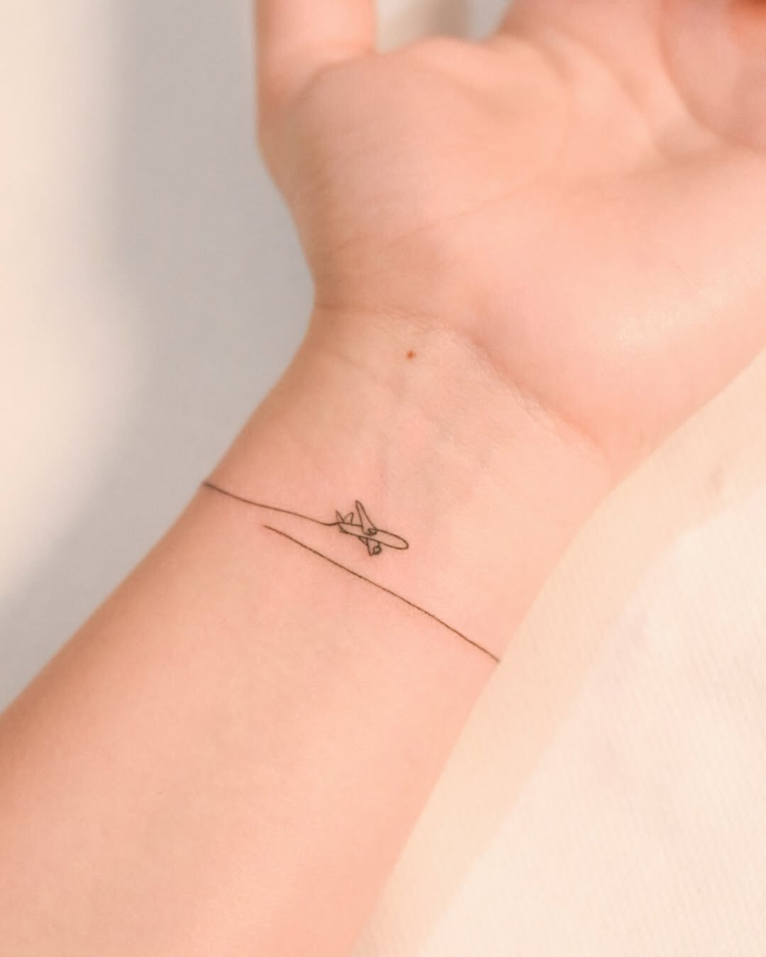 Minimalist airplane tattoo on the wrist Tattoo Design