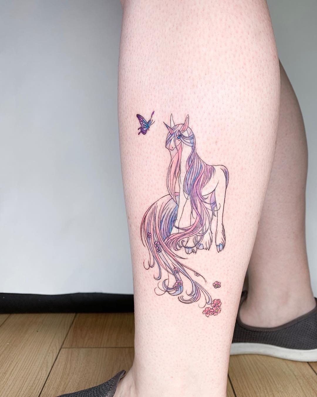 Whimsical unicorn tattoo with floral accents Tattoo Design