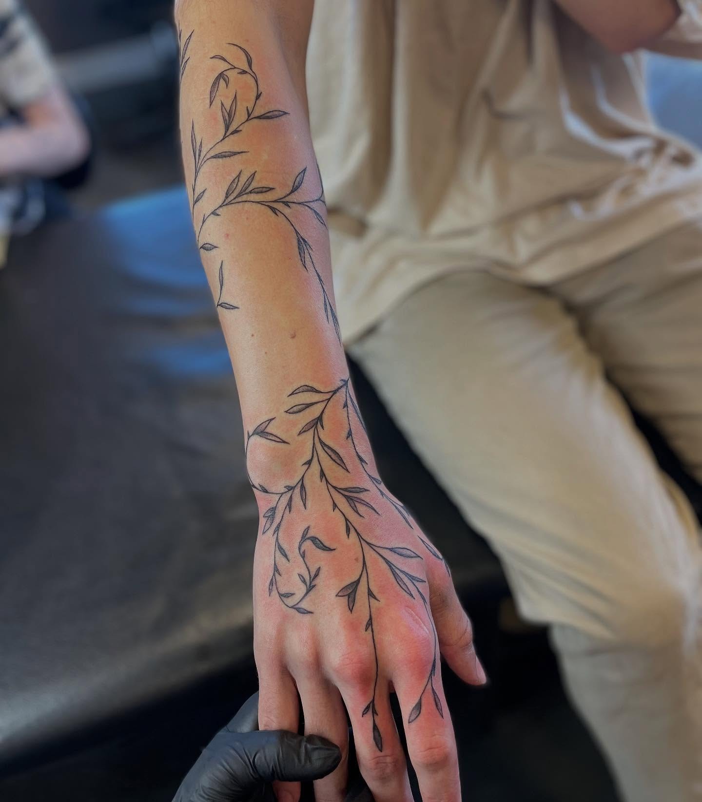 Minimalist Vine Tattoo Flowing from Arm to Hand Tattoo Design