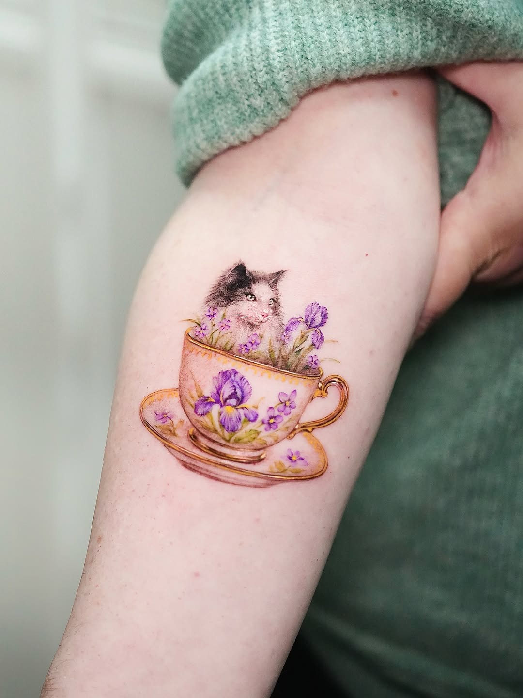 Charming violet-themed cat in a teacup tattoo Tattoo Design