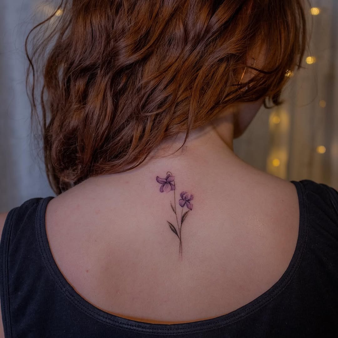 Delicate violet flowers inked on the back Tattoo Design