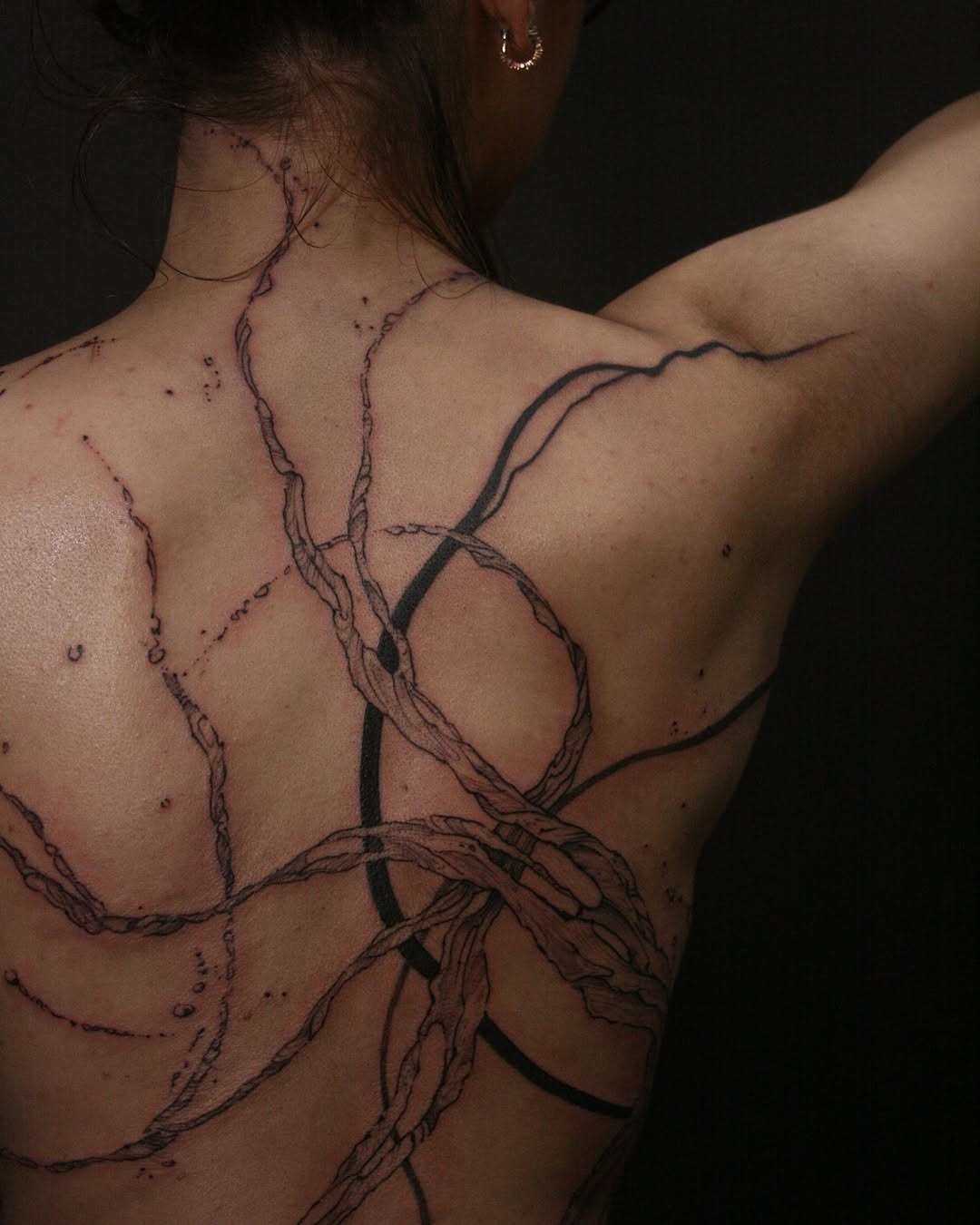 Intricate water-inspired tattoo on the back Tattoo Design