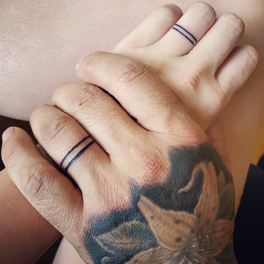Minimalist wedding ring tattoos on couple's hands Tattoo Design