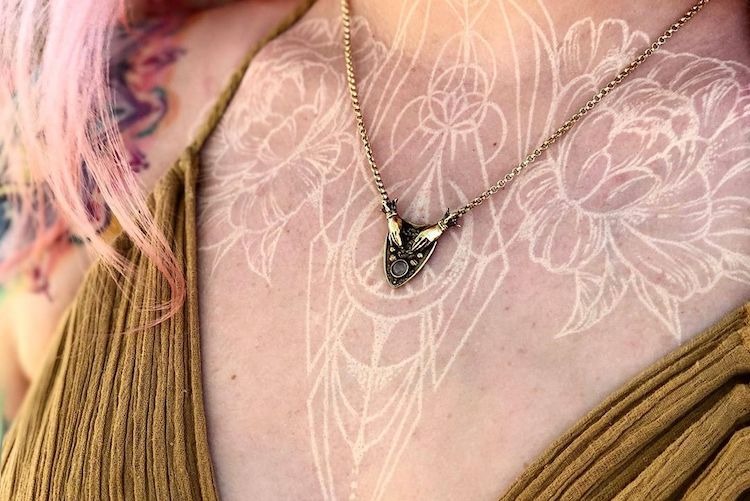 A Modern Floral White Ink Tattoo Design on the Chest Tattoo Design