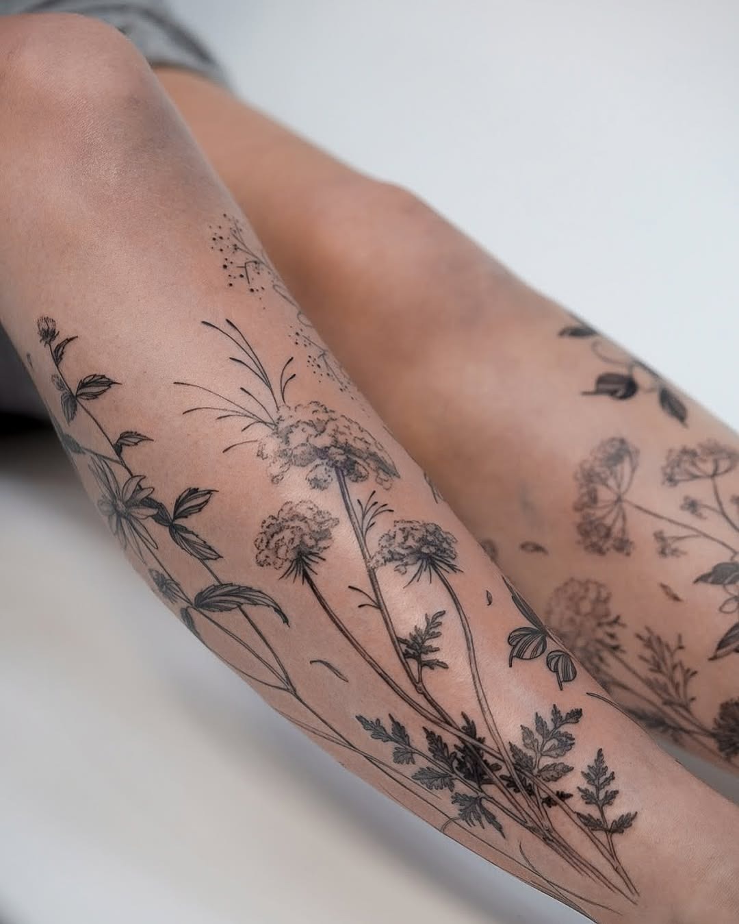 Elegant wildflower tattoos grace the legs. Tattoo Design