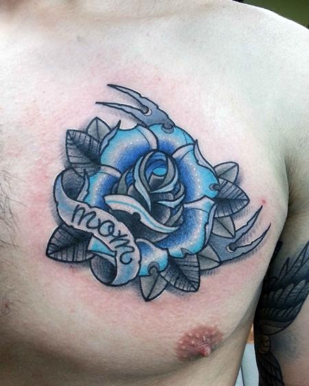 This chest tattoo features a striking blue rose at its center, surrounded by detailed black thorns that give it an edge of strength and protection.