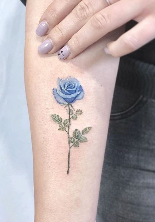 This design focuses on a blue rose with a realistic stem and leaves, adding a naturalistic element to the tattoo.