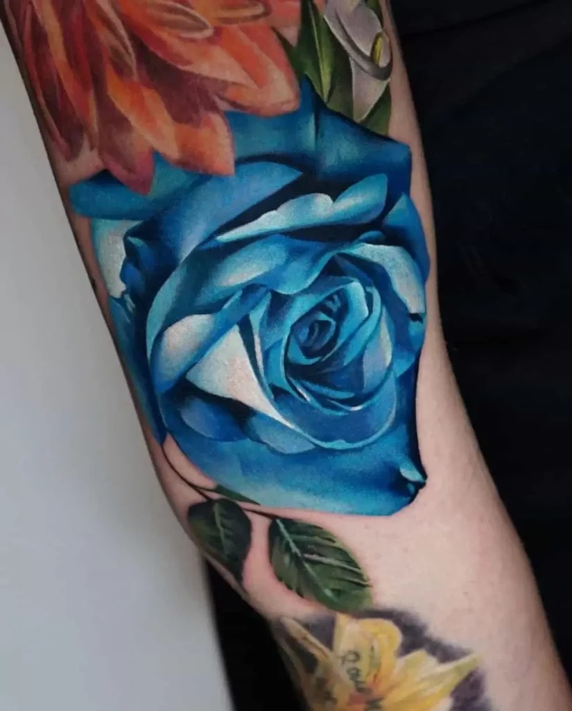 This blue rose tattoo stands out for its color saturation and intricate shading.