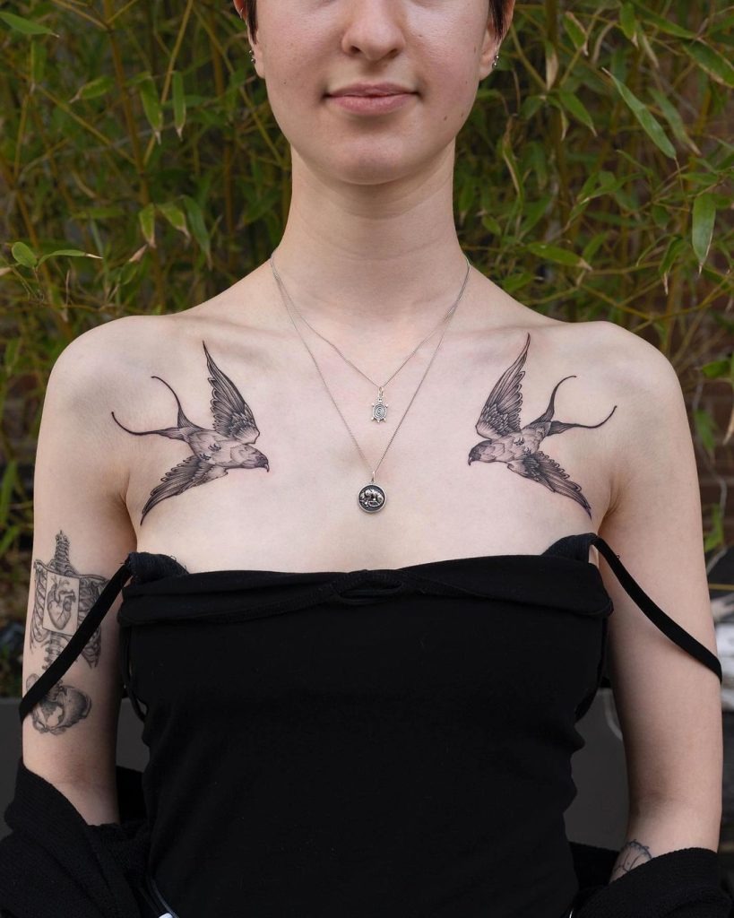 This chest tattoo showcases two birds in mid-flight, positioned symmetrically on each side of the chest.