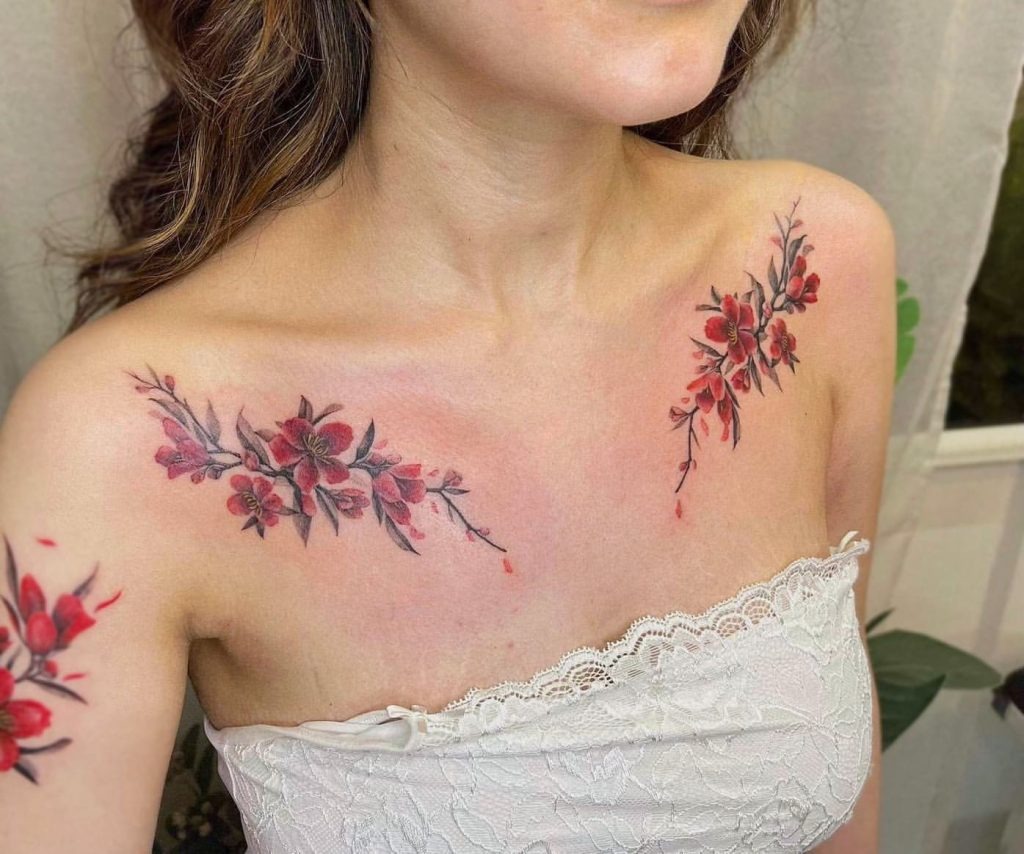 This tattoo captures the eye with its hues, creating a striking floral arrangement across the collarbones.