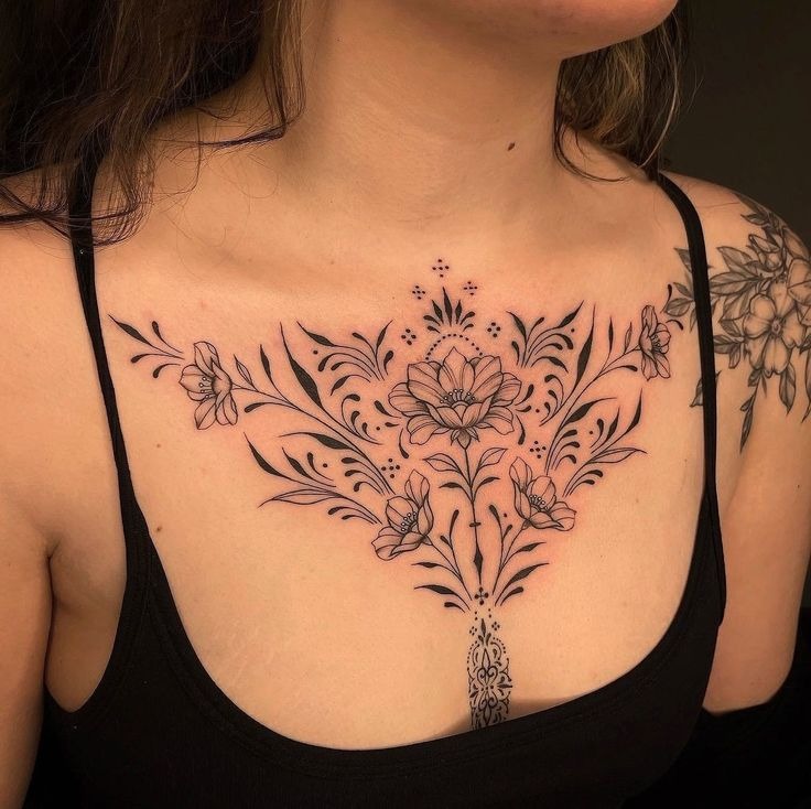 This tattoo features a symmetrical arrangement of floral elements cascading down the chest.