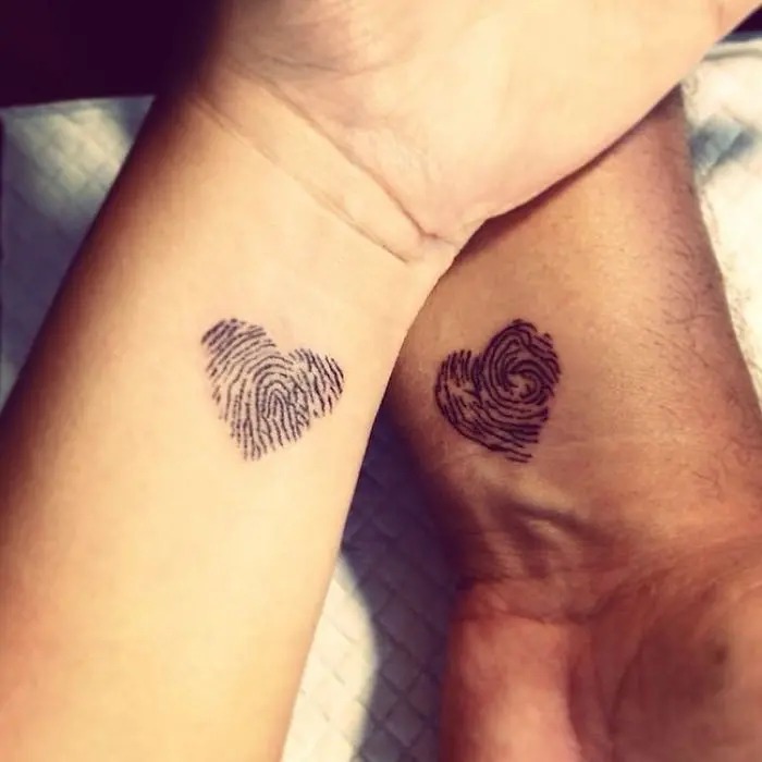 This unique tattoo design features two heart shapes composed of fingerprint patterns, symbolizing the individuality and personal connection between two people.