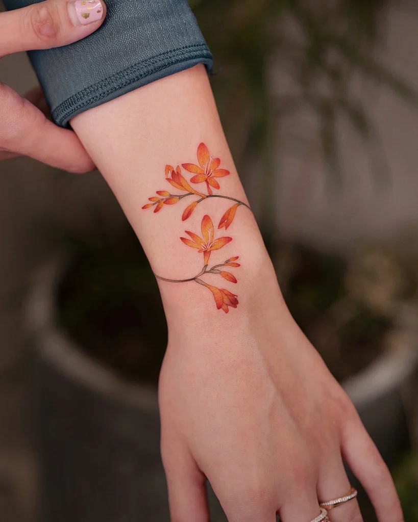 Inspired by the warm hues of autumn, this floral tattoo features blossoms in shades of orange and red, symbolizing change and the beauty of letting go.