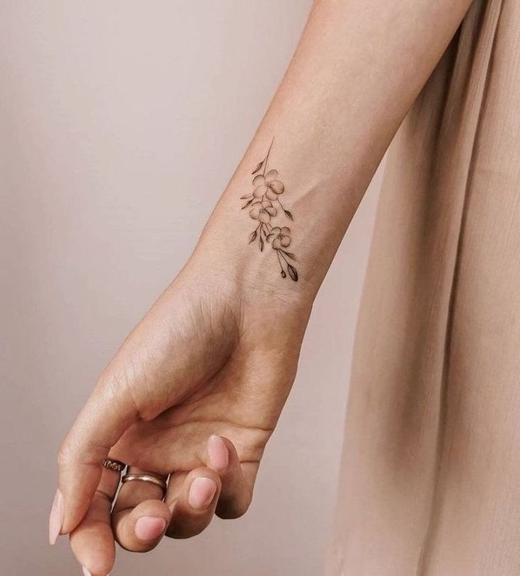 A floral vine tattoo offers a soft, feminine touch to the wrist.